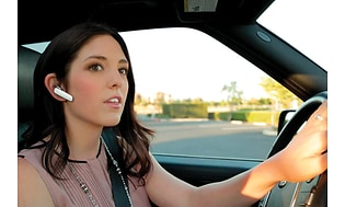 Kvinne har på seg hodetelefoner mens hun kjører bil