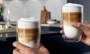 To hender som holder to kopper kaffe med melkeskum