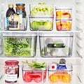 Åpent kjøleskap med mat i gjennomsiktige bokser