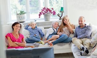 Familie som sitter i sofaen foran en TV
