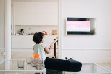 Liten jente holder fjernkontrollen foran en TV
