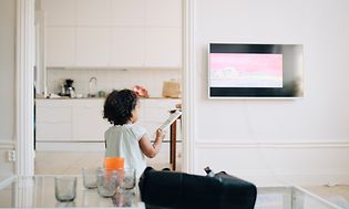 Liten jente holder fjernkontrollen foran en TV