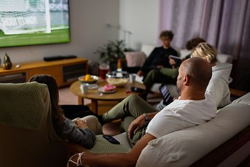 Familie i sofa ser på sport på TV