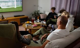 Familie i sofa ser på sport på TV
