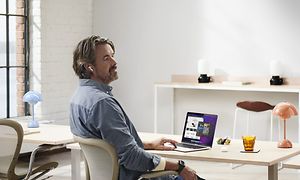 mann sitter ved et skrivebord og jobber på sin macbook