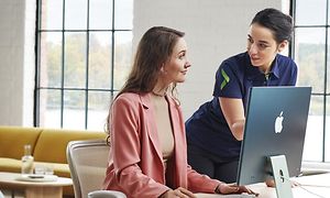 kvinnelig elkjøp-ansatt hjelper kvinne å bruke sin imac