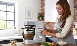 Kvinne som trykker på CookAssist-berøringsskjermen på en Kenwood Cooking Chef XL kjøkkenmaskin