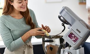 Kvinne som putter smør i bakebollen til en Kenwood Cooking Chef XL kjøkkenmaskin