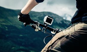 Mann utendørs ser på en fjellutsikt med actionkamera montert på sykkelen
