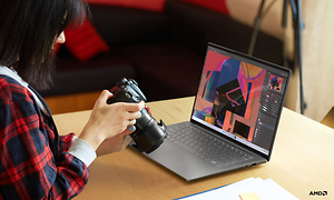 Kvinne holder DSLR-kamera foran en Yoga Slim 7 Pro X bærbar PC