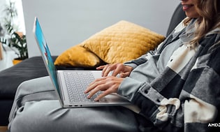 Kvinne i en sofa med en Lenovo Yoga Slim 7 Carbon bærbar PC på fanget