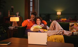 Par som sitter i en sofa og ser på en film på en Lenovo Yoga Slim 9