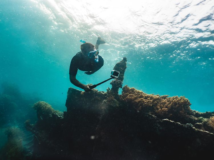 Mann dykker på korallrev og filmer med GoPro-actionkamera