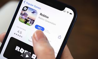 En hånd som holder en telefon som installerer  Roblox fra App Store