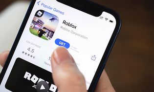 En hånd som holder en telefon som installerer Roblox fra App Store