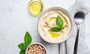 Hummus i en skål med olivenolje og kikerter ved siden av