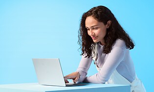 Kvinne som står og bruker en liten bærbar datamaskin