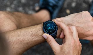 en mann sjekker smartklokke på håndledd