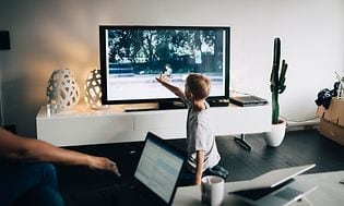 Liten gutt peker på skjermen på en TV