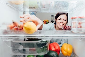 kvinne strekker seg inn etter en sitron i kjøleskap