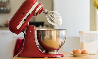 KitchenAid kjøkkenmaskin på kjøkkenbenk med egg og boks med sukker