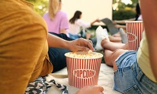 Cuople eating popcorn and watching screen outside
