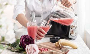 En kvinne på et kjøkken som heller rosa juice fra blenderbeholderen fra Ankarsum i et glass