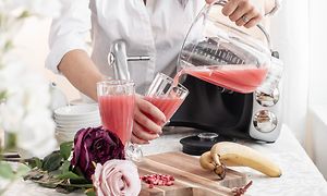  En kvinne på et kjøkken som heller rosa juice fra blenderbeholderen fra Ankarsum i et glass