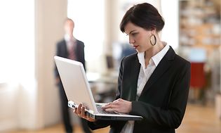 Kvinne i dress som holder en bærbar datamaskin