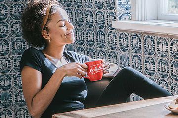 Kvinne som drikker fra kaffekopp med kaffemaskin på bordet