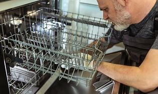 mann reparerer en oppvaskmaskin
