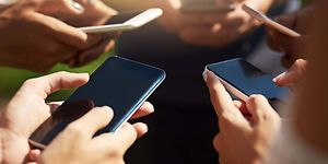 en gruppe personer står sammen og bruker smarttelefon utendørs