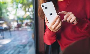 en kvinne holder og bruker en iPhone 13