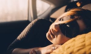 En kvinne som sover i en bil med en sovemaske
