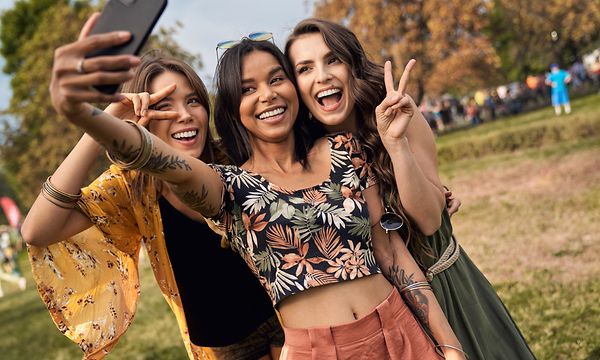 tre jenter tar selfie sammen med en smarttelefon