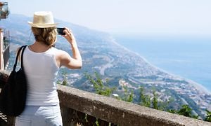 Kvinne på ferie som bruker smarttelefonen til å ta bilde av kystlinjen