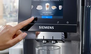 Finger som trykker på skjermen til en Siemens EQ700 espressomaskin