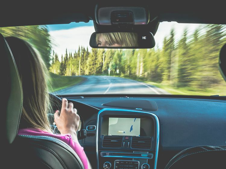 kvinne kjører bil med GPS på