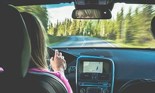 kvinne kjører bil med GPS på