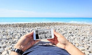 en mann ligger på stranda og sjekker overvåkningskameraet fra sitt hjem