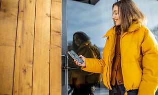 en kvinne låser en smart lås på utgangsdør med smarttelefon