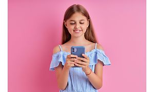 en liten jente holder en mobiltelefon med silikondeksel på
