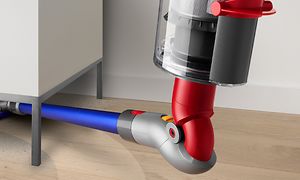 Nærbilde på en Dyson V10-støvsuger som støvsuger under møbler med den bøybare adapteren som
