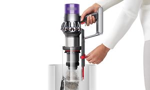 En kvinne tømmer støvbeholderen på en Dyson V10 som illustrerer "point and shoot"-mekanismen