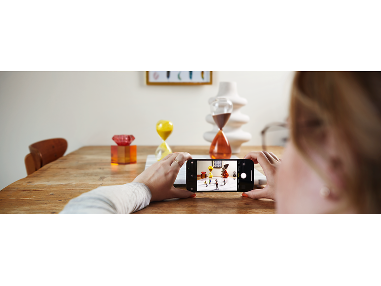 kvinne tar bilde av ting på et bord med sin iphone