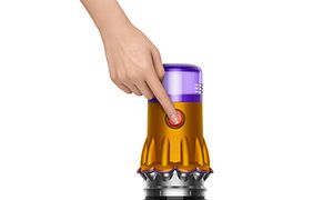 En hpnd som trykker på av og på-knappen på en Dyson V12 Slim 