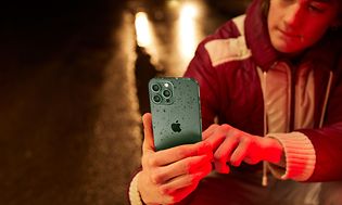 en tenåring tar bilder med en iPhone 13 Pro Max med dråper på