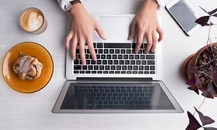 Woman using laptop with accessories around her on the table