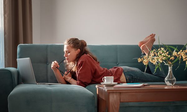 Girl laying on a couch using a laptop