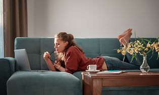 Girl laying on a couch using a laptop